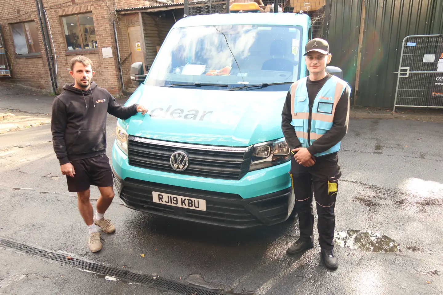 Two people in Clear It clothing beside the company van