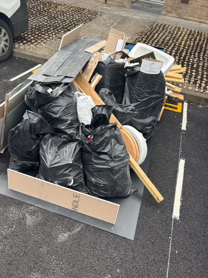 Bagged waste, timber, panels and sanitaryware in a parking space.