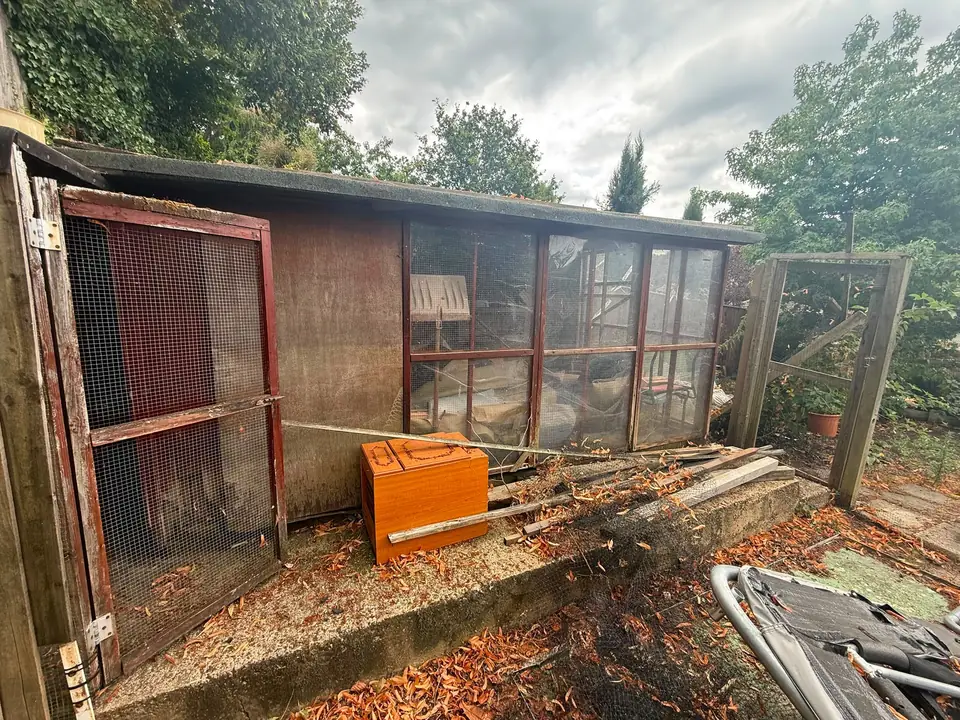 Timber and wire-mesh garden structure before removal.